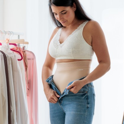 Frau zieht Hose über ihre Shapewear an Shapewear 