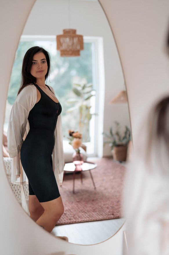 Frau im Kompressionsbody posiert im Spiegel