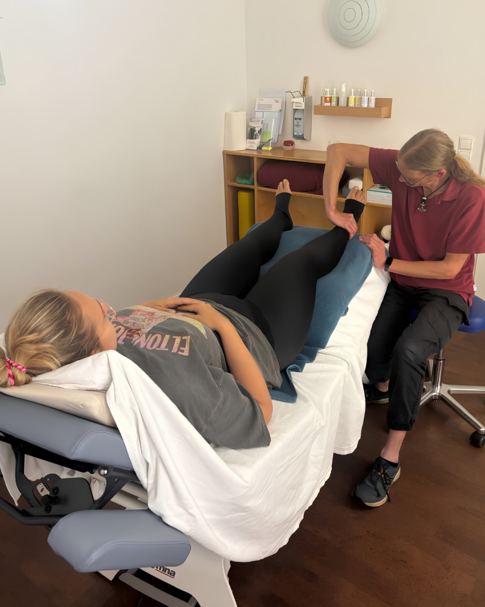 Juliane ist bei der Physiotherapie und liegt auf einer Liege, während die Physiotherapeutin an ihren Beinen manuelle Lymphdrainage macht.